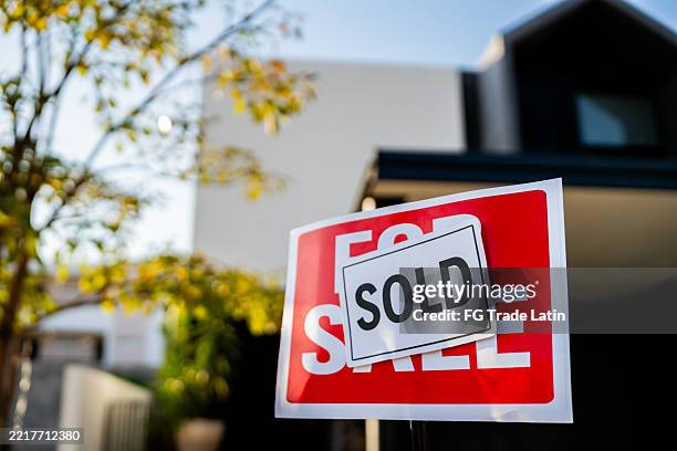house with for sale sign and "sold" sticker above the sign in the front yard - estate agent sign stock pictures, royalty-free photos & images