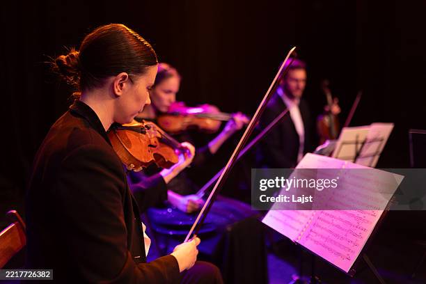 eine konzentrierte geigerin schaut während eines streichquartett-konzerts auf die noten auf dem ständer vor ihr - notenständer stock-fotos und bilder