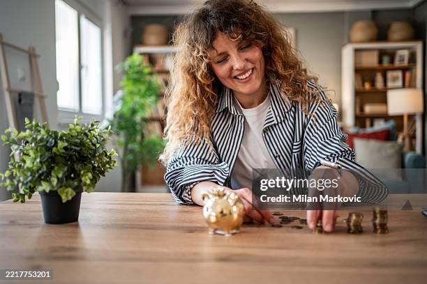 woman saving money at home using piggy bank - counting stock pictures, royalty-free photos & images