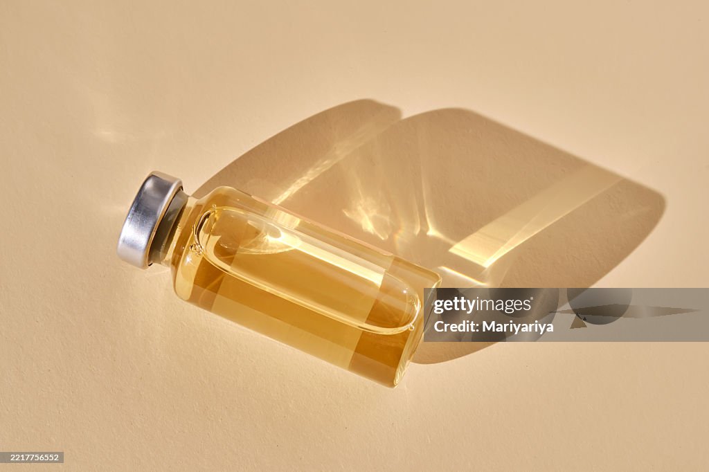 Injection vial on beige background.