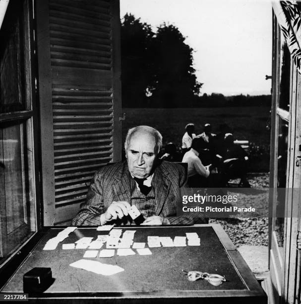 French poet, playwright and diplomat Paul Claudel plays a game of solitaire by an open doorway, circa 1950.