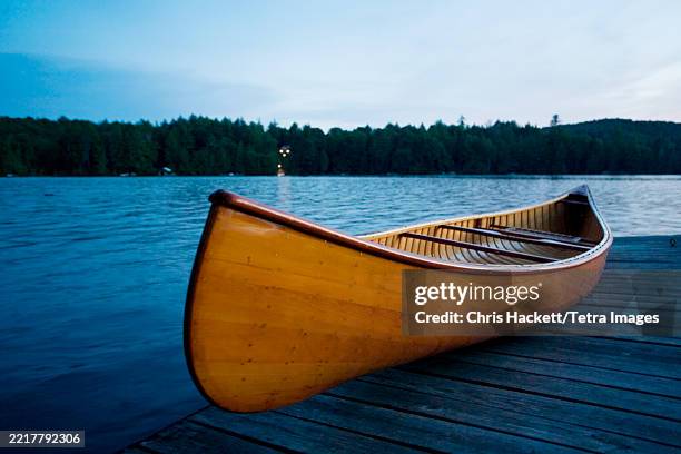 Canoe On Jetty On Calm Lake At Dusk, Stockfoto