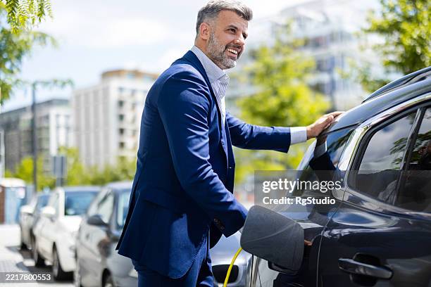 businessman stopped to recharge his electric car - battery life stock pictures, royalty-free photos & images