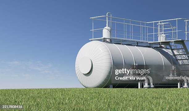 fuel storage tanks in a grassy field under a blue sky - benzintank stock-fotos und bilder