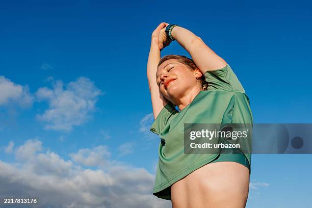 young woman stretching before jogging outdoors - aquecimento físico imagens e fotografias de stock