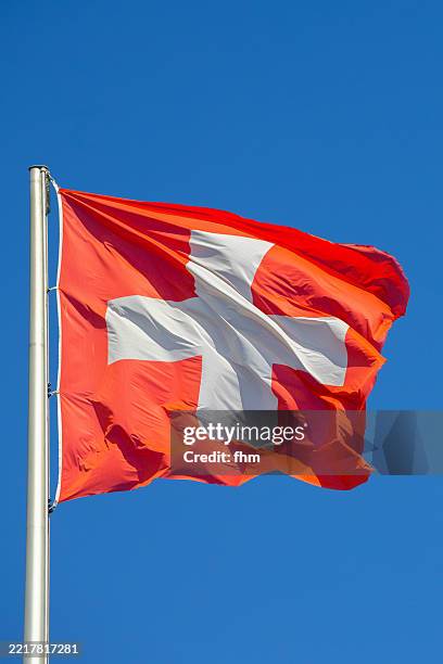 swiss national flag against blue sky - schweizer flagge stock-fotos und bilder