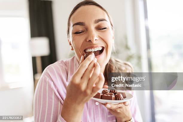woman eating chocolate with joy - eating chocolate stock pictures, royalty-free photos & images
