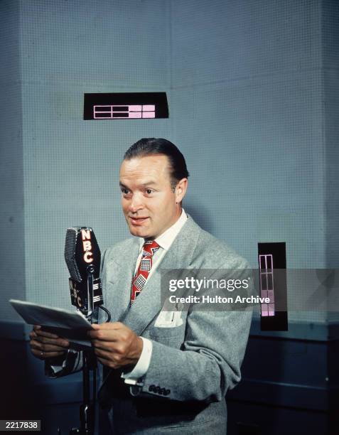 British-born comedian and actor Bob Hope speaks with a script at an NBC radio microphone, 1940s.