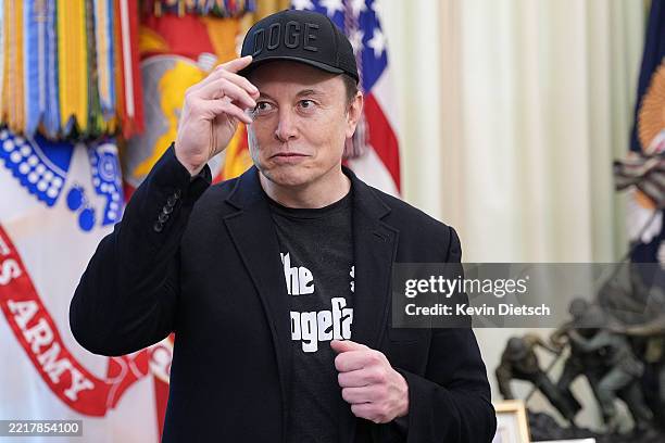 Tesla CEO Elon Musk removes his hat as he listens to a question from a reporter alongside U.S. President Donald Trump in the Oval Office of the White...