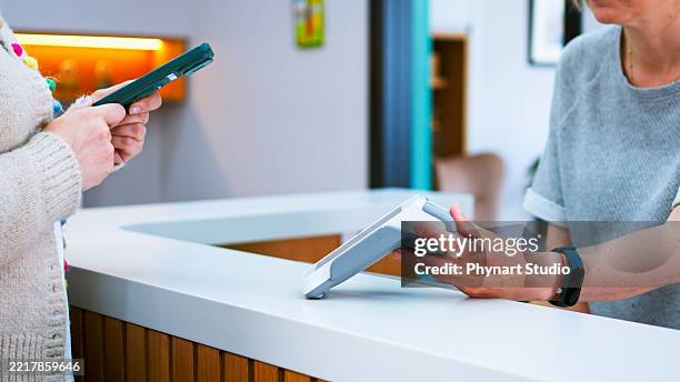 patient is making mobile payment at a hospital reception - veterinary receptionist stock pictures, royalty-free photos & images