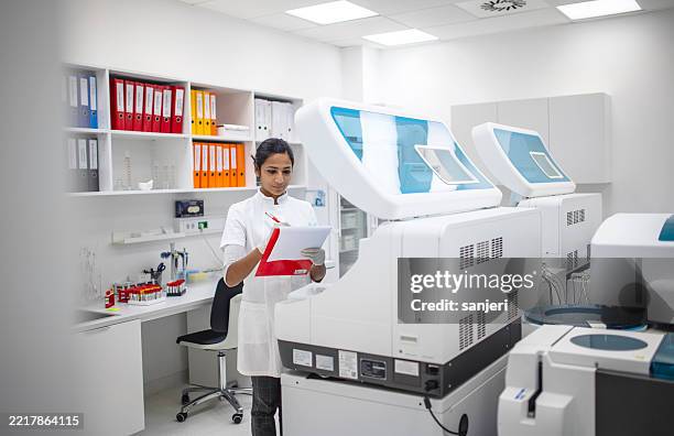 junger medizinischer forscher im weißen laborkittel arbeitet mit fortschrittlichen diagnosegeräten im klinischen labor - nanomedizin stock-fotos und bilder