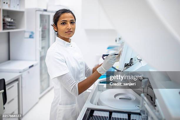 young female scientist operating laboratory equipment in modern medical research facility - biochemist stock pictures, royalty-free photos & images