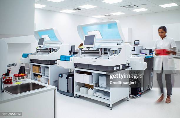 junger medizinischer laborfachmann, der mit fortschrittlichen diagnosegeräten in einem modernen klinischen labor arbeitet - nanomedizin stock-fotos und bilder