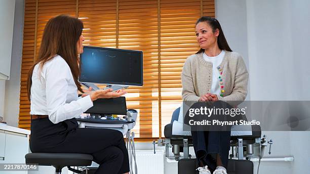 female doctor consulting patient during ultrasound examination in modern clinic - colposcopy stock pictures, royalty-free photos & images