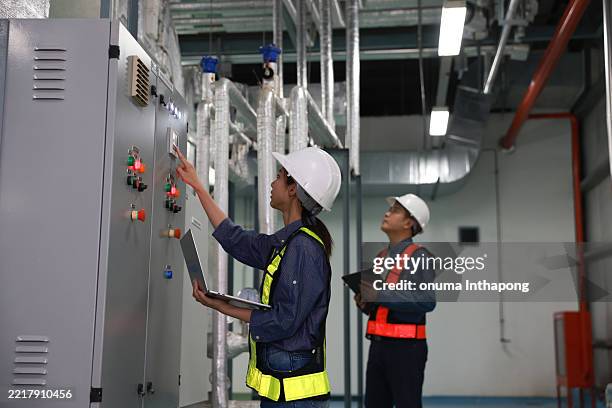 electrical engineer team wearing safety vest and white hardhat check control switchgear or mdb and record to laptop and digital tablet - electricity transformer stock pictures, royalty-free photos & images