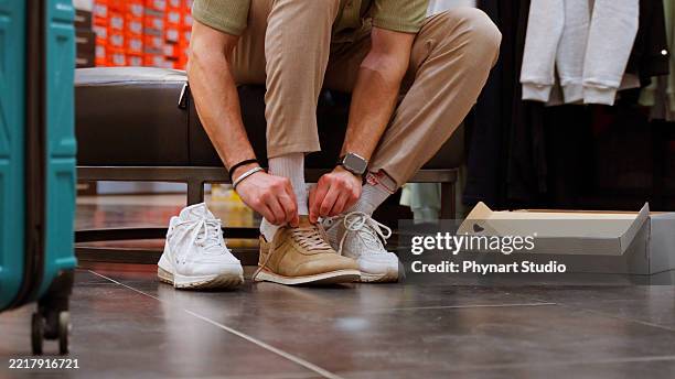 client un jeune homme essaie une nouvelle paire de chaussures dans un magasin de chaussures - chaussures photos et images de collection