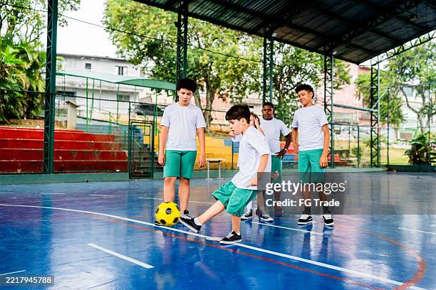kinder spielen fußball während des sportunterrichts auf dem sportplatz in der schule - außerschulische aktivität stock-fotos und bilder