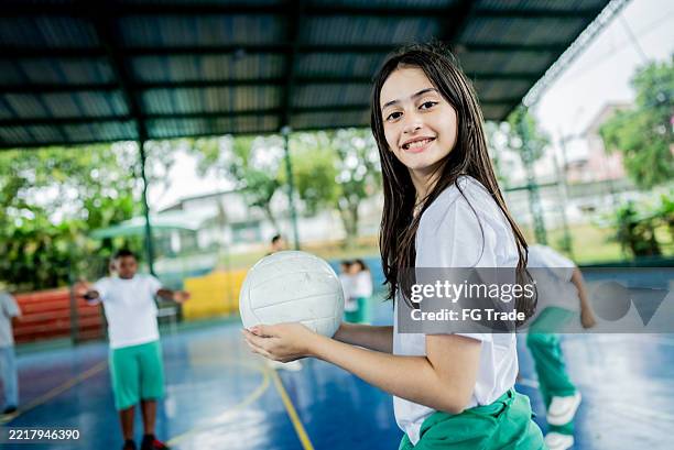 portrait of schoolgirl holding volleyball on the sports court at school - endast flickor bildbanksfoton och bilder