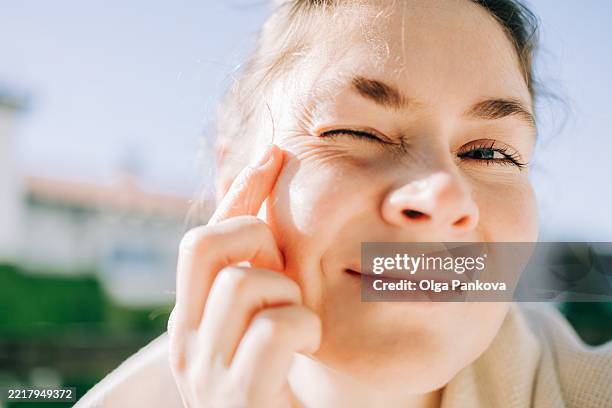 close-up of mid woman smiling and touching her face with wrinkles - luz ultravioleta eletromagnético imagens e fotografias de stock