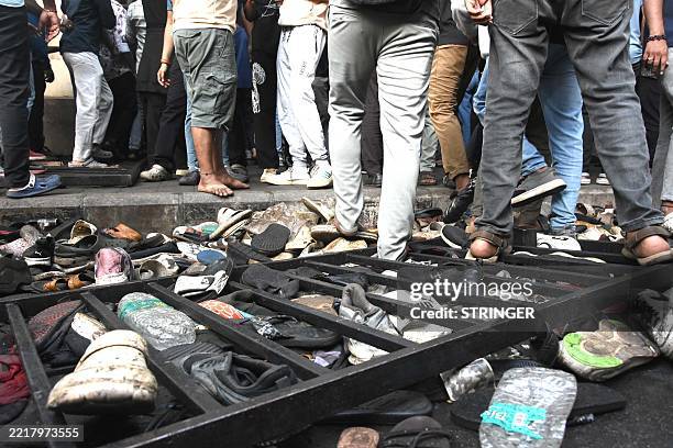 Fans stand next to abandonned shoes and a fallen barrier following a stampede during celebrations, a day after Royal Challengers Bengaluru's victory...