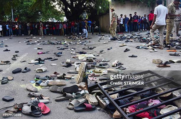 Fans stand next to abandonned shoes and a fallen barrier following a stampede during celebrations, a day after Royal Challengers Bengaluru's victory...