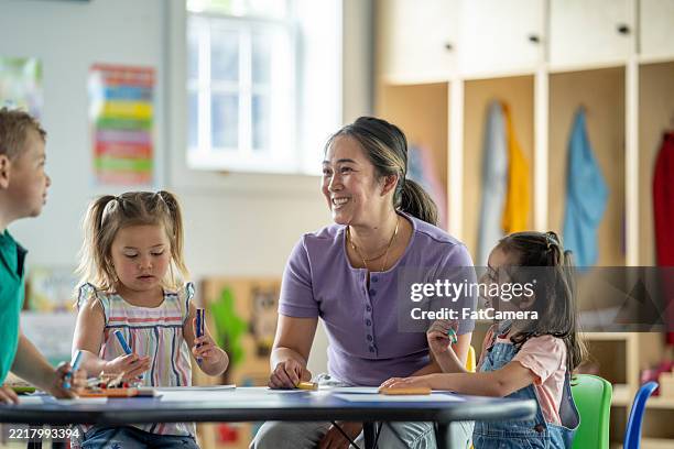 teacher interacting with young children in a cheerful classroom setting - words of support and encouragement stock pictures, royalty-free photos & images