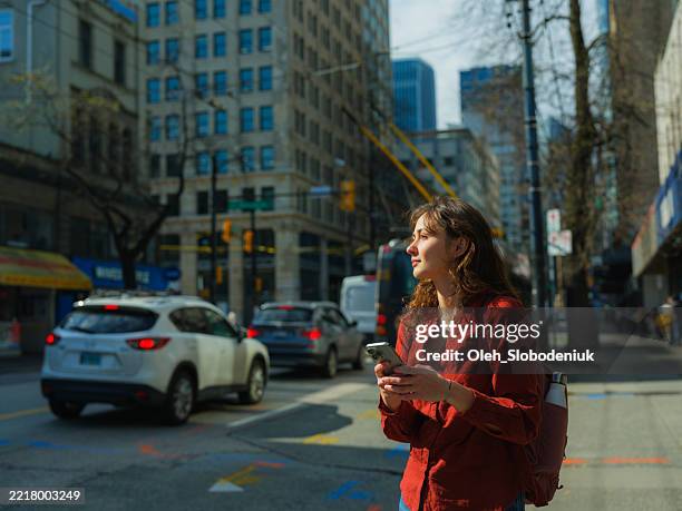 woman using smartphone walking in vancouver downtown - solo travel stock pictures, royalty-free photos & images