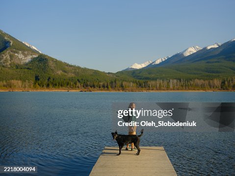 Woman with dog on the pier on Vermillion Lake in Banff, Canada Woman with dog on the pier on Vermillion Lake in Banff, Canada