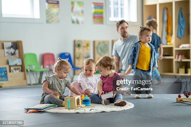 grupo de niños jugando en un ambiente de guardería luminoso y alegre - escuela preescolar fotografías e imágenes de stock