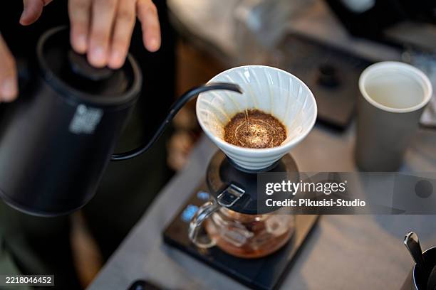 barista brewing pour-over coffee with ceramic dripper and glass server - brewery stock pictures, royalty-free photos & images