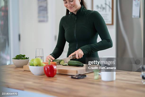 woman preparing fresh vegetables in a modern kitchen interior - athleisure stock pictures, royalty-free photos & images