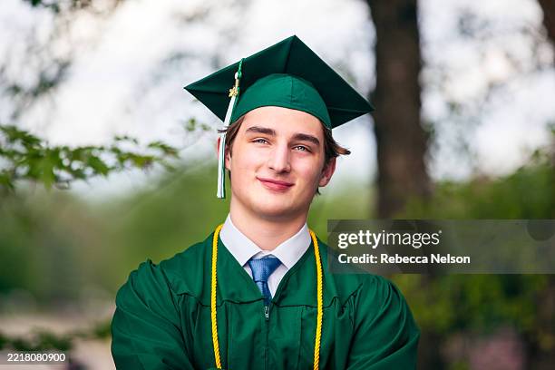 high school senior boy in cap and gown on graduation day - laatstejaars high school stockfoto's en -beelden