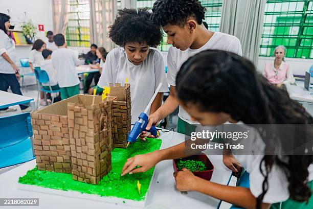 group of students preparing a model of a castle in the classroom - preteen models | young nonude teen models imagens e fotografias de stock