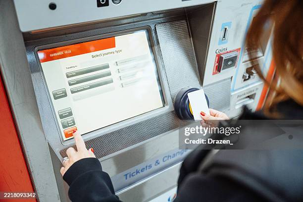 mid adult woman buying transportation tickets on the vending machine at railway station - ticket vending machine stock pictures, royalty-free photos & images