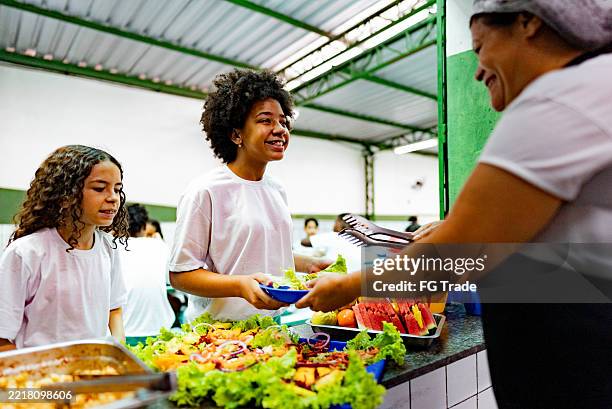 schülerinnen erhalten ein gesundes mittagessen in der cafeteria der schule - kantinenfrau stock-fotos und bilder