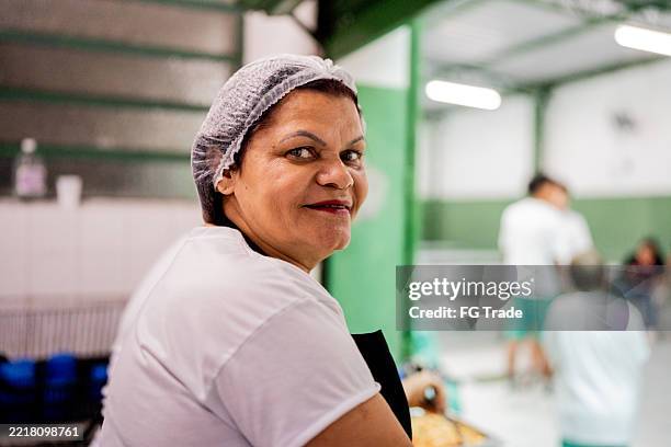 porträt eines schulkochs, der während des mittagsdienstes in der cafeteria lächelt - kantinenfrau stock-fotos und bilder