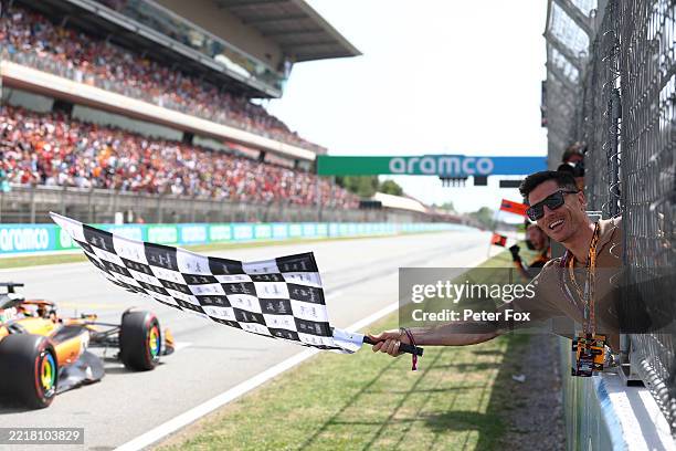 Robert Lewandowski waves the chequered flag as Race winner Oscar Piastri of Australia and McLaren takes victory during the F1 Grand Prix of Spain at...