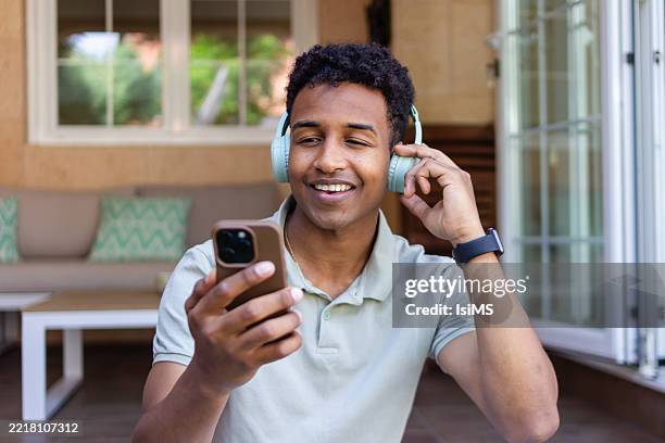 young man enjoying music on his phone with headphones - muziekstreamingdienst stockfoto's en -beelden