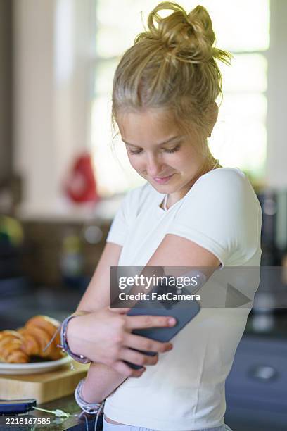young woman using a glucose monitor at home holding her smartphone - glycemia stock pictures, royalty-free photos & images