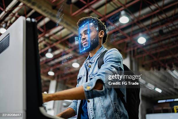 mann im mittleren erwachsenenalter, der sich beim check-in am flughafen einer gesichtserkennung unterzieht - gesichtserkennung stock-fotos und bilder