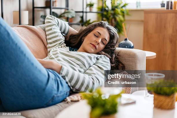 young woman sleeping on the sofa at home - napping stock pictures, royalty-free photos & images