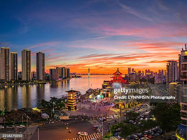 panoramic view of city waterfront at sunset with traditional - style architecture - insel hainan stock-fotos und bilder
