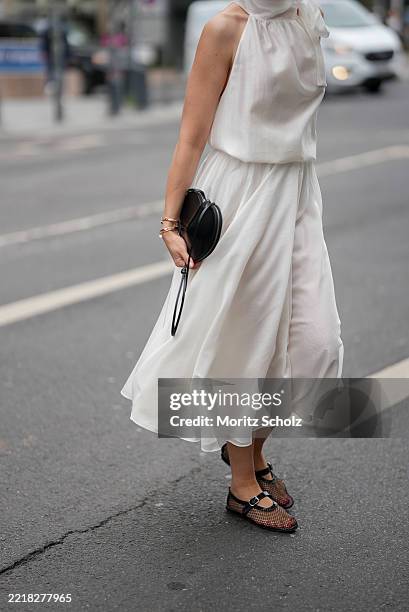 Patricia Wirschke is seen wearing a white two-piece consisting of a flowy midi skirt and a sleeveless blouse with high collar and tie detail at the...