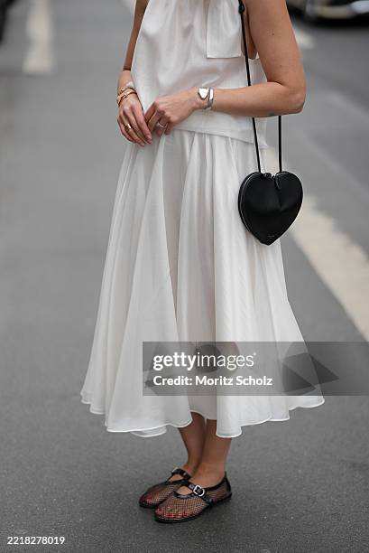 Patricia Wirschke is seen wearing a white two-piece consisting of a flowy midi skirt and a sleeveless blouse with high collar and tie detail at the...