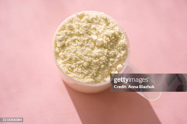 measuring scoop of whey protein powder on pink table in bright sunlight - powder foto e immagini stock