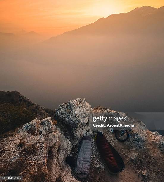 camping with bicycles on bluff above lake at sunset - sleeping bag stock pictures, royalty-free photos & images
