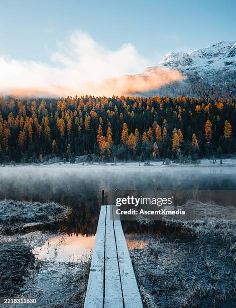 boardwalk over lake below mountains at sunrise - cantão de graubünden imagens e fotografias de stock