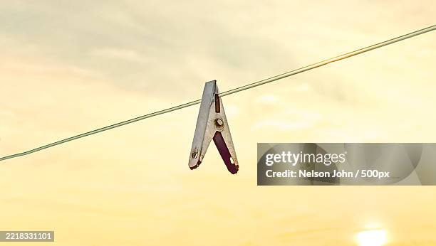 low angle view of clothespin hanging on clothesline against sky - clothespin stock pictures, royalty-free photos & images