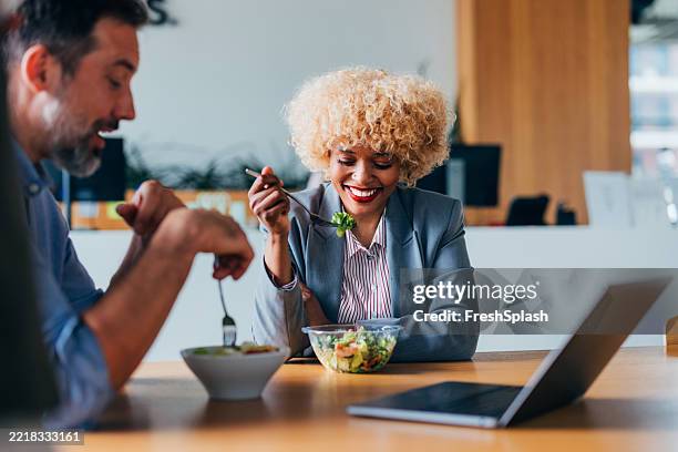 colleghi che si godono una sana pausa pranzo insieme in un ambiente d'ufficio luminoso - pausa pranzo foto e immagini stock