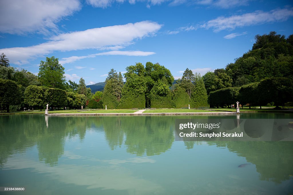 The reflection pond and elegant sculptures create a tranquil scene within the gardens of Schloss Hellbrunn in Salzburg, Austria.